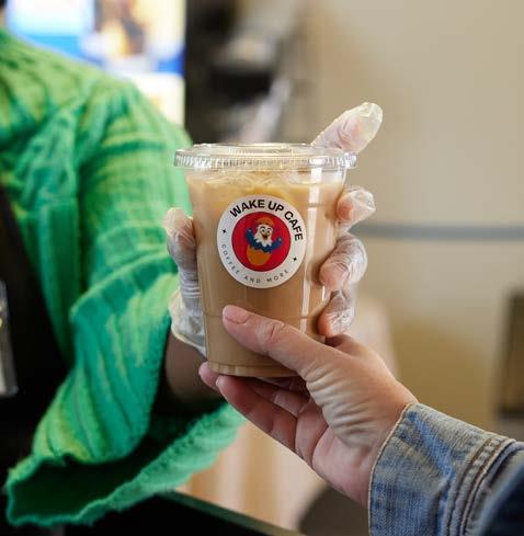  Two hands exchange a cup of iced coffee with a café logo on it.